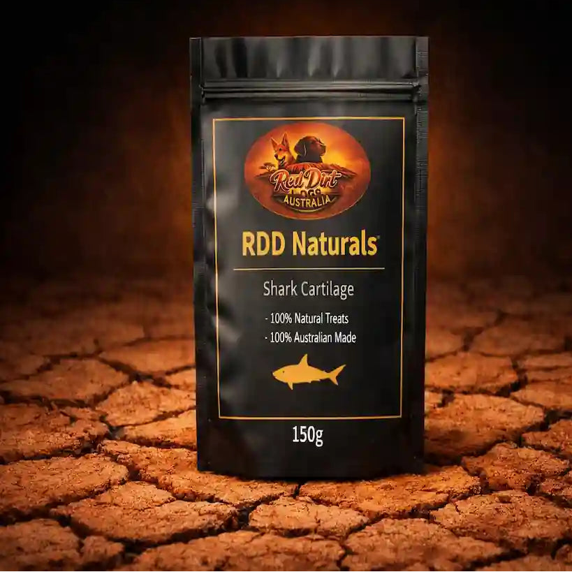 A black stand-up pouch labeled RDD Naturals Shark Cartilage, 150g, standing on cracked earth against a dark background. The pouch has gold text and a gold fish icon, with a circular logo at the top.
